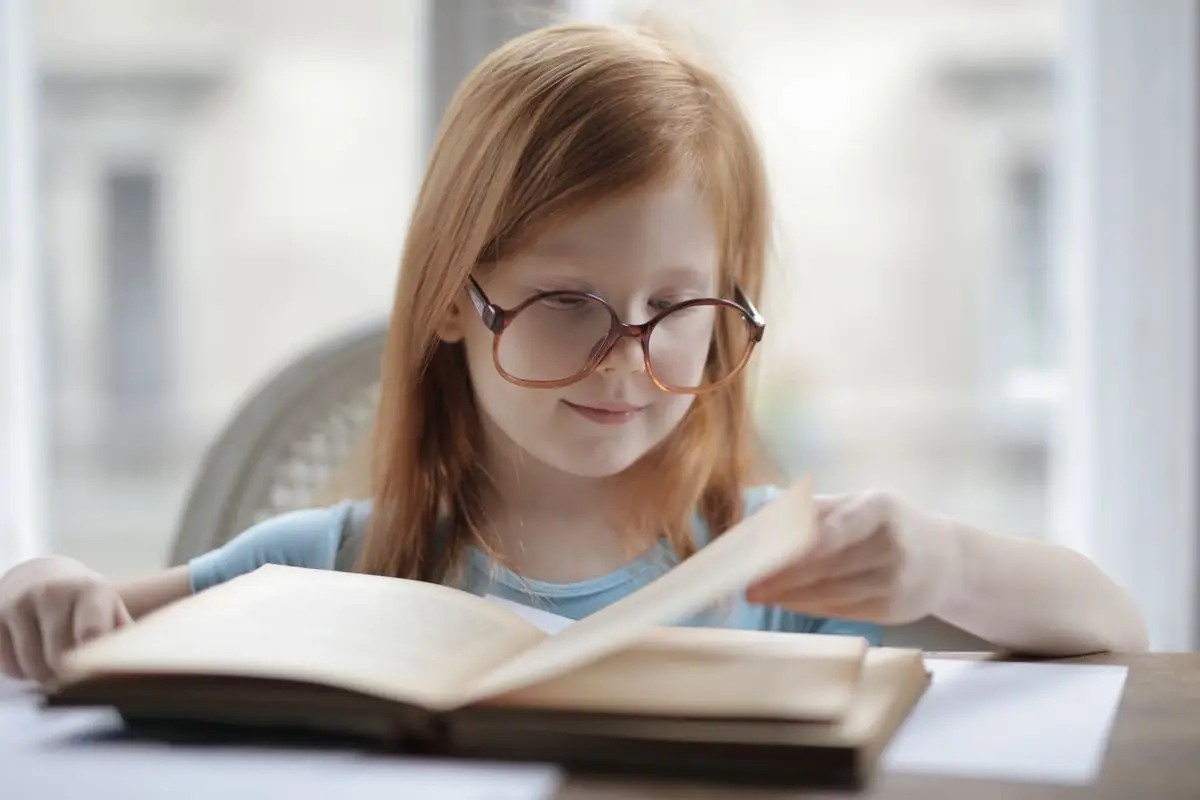 A girl wearing glasses reading at a desk