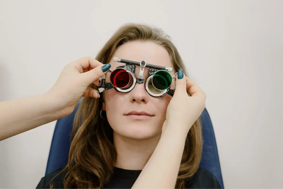An optometrist fitting a trial frame with red and green lenses during a sight test